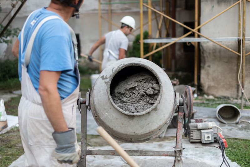 concrete mixer and two workers at a construction site